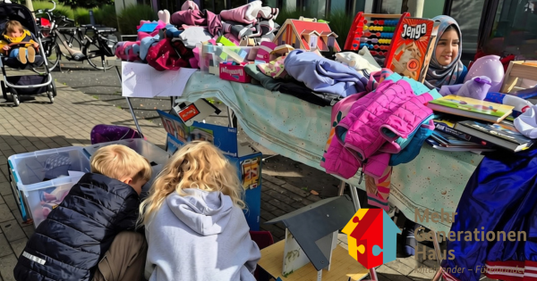 Zwei Kinder suchen sich etwas aus an einem Flohmarkt Tisch